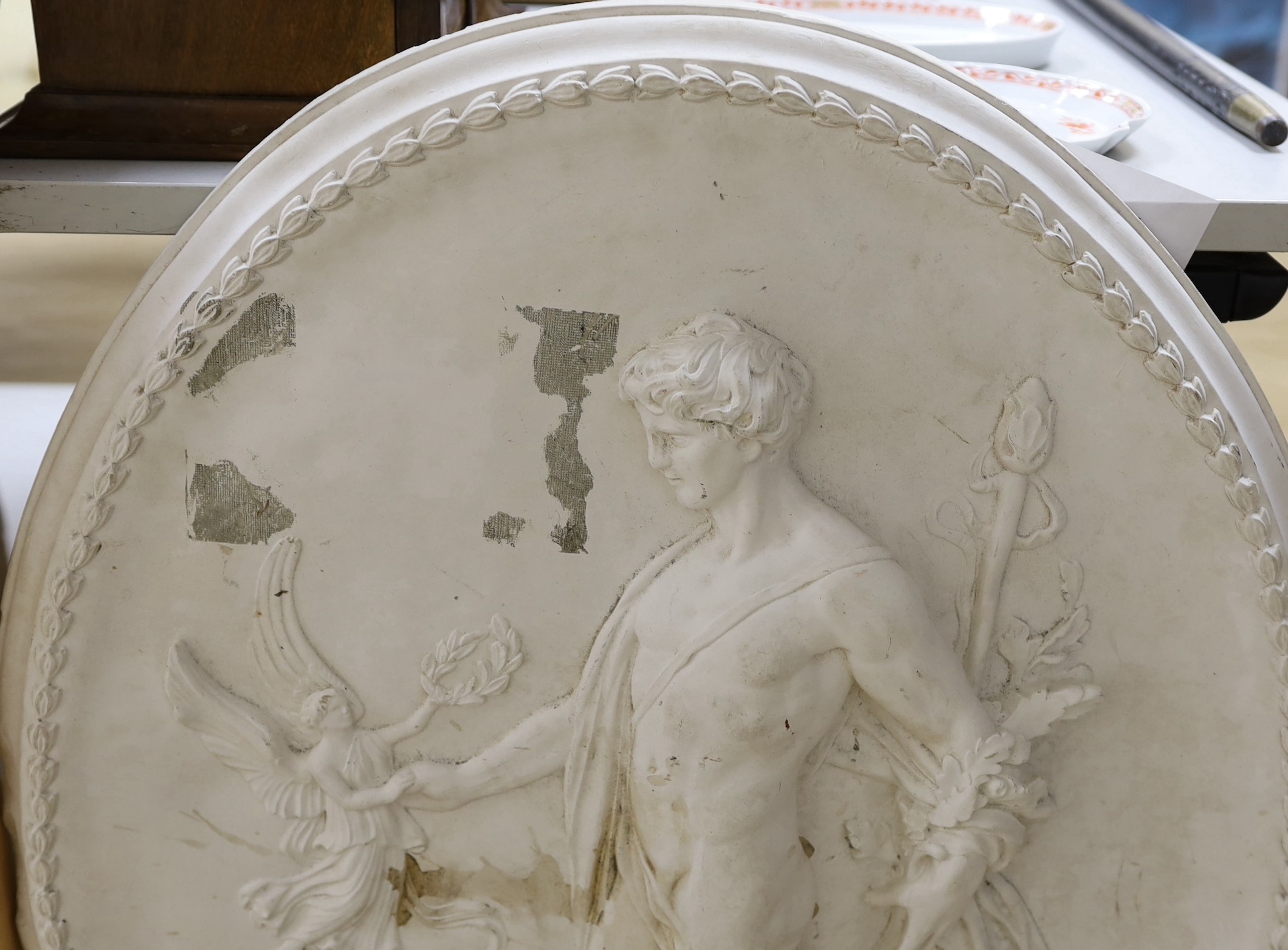 A cast plaster oval figural plaque